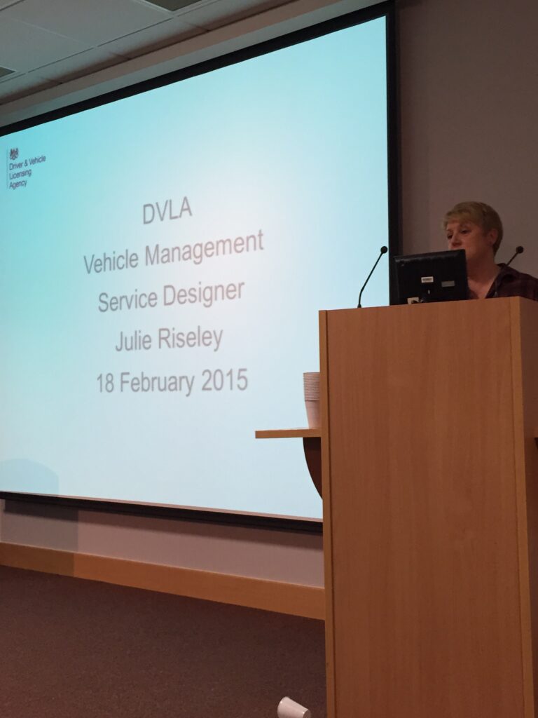 Julie Risley standing behind a lectern delivering a presentation 