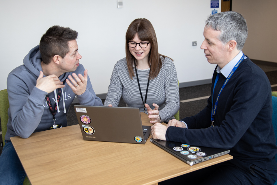 3 DVLA service designers working on new Vehicle Enquiry Service API around a laptop