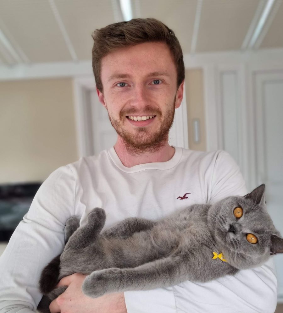 Person in white jumper holds a cat.