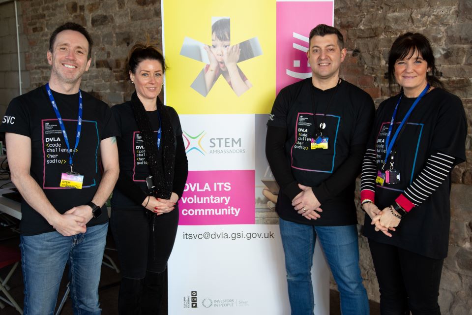 Four people standing next to a board promoting the STEM programme.