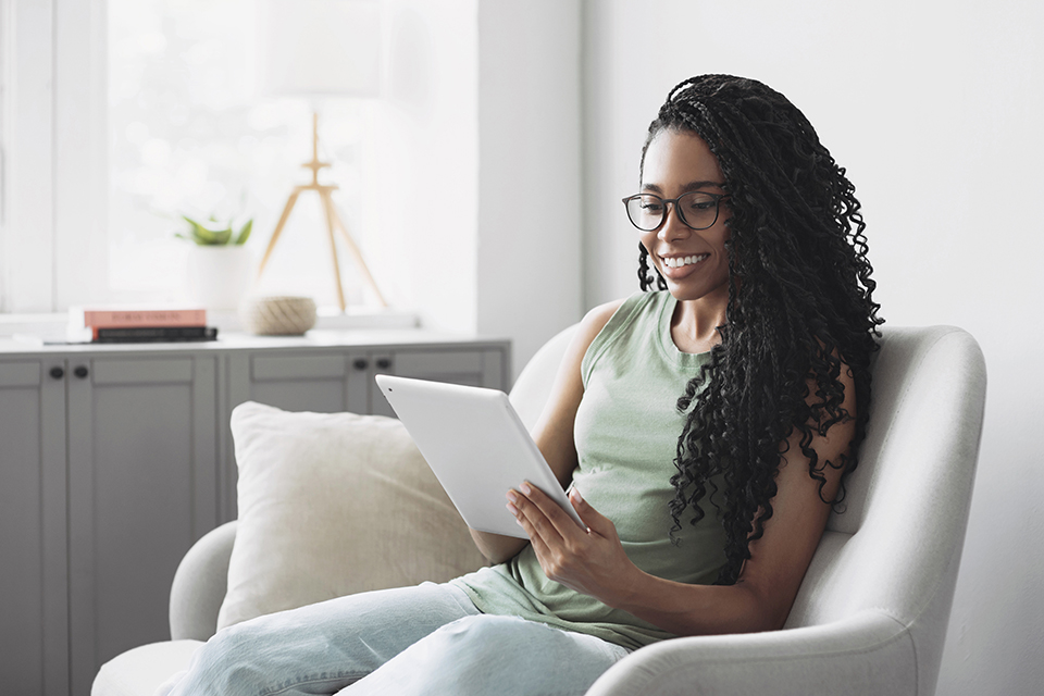 Woman sitting in a chair and using a tablet.